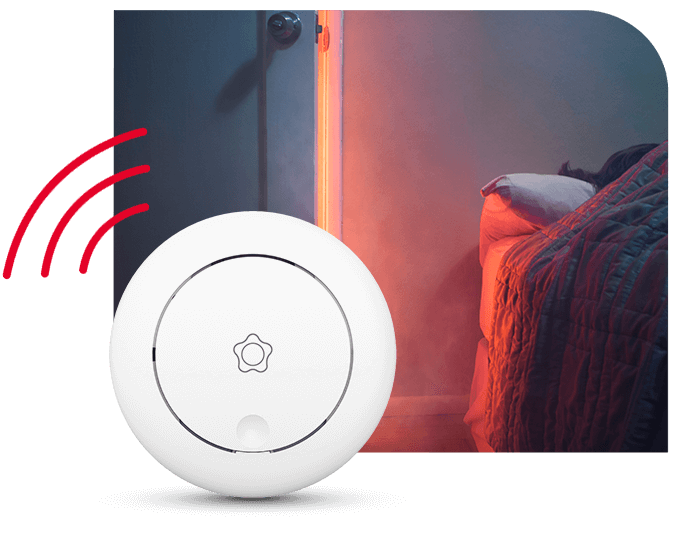 Etualalla Verisuren sarjaan kytketty optinen palovaroitin, takana tulipalon alku makuuhuoneessa.