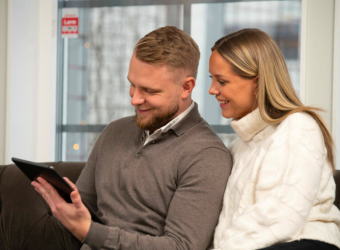 Pariskunta istuu sohvalla ja katsoo tablettia.