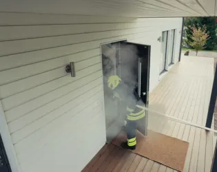 Taustalla palomies avaa oven koiralle. Etualalla teksti: "Apu paikalla. Koira pelastettu."