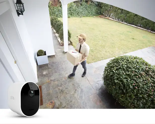 Arlo-valvontakamera ja taustalla lähetti ulko-oven edessä tuomassa pakettia.