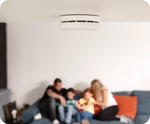 Perhe istuu sohvalla Verisuren palovaroittimilla suojatussa kodissa.