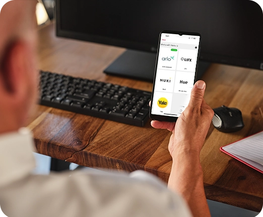 Mies puhelin kädessä, jossa näkyy Works with Verisuren kanssa yhteensopivia tuotemerkkejä.