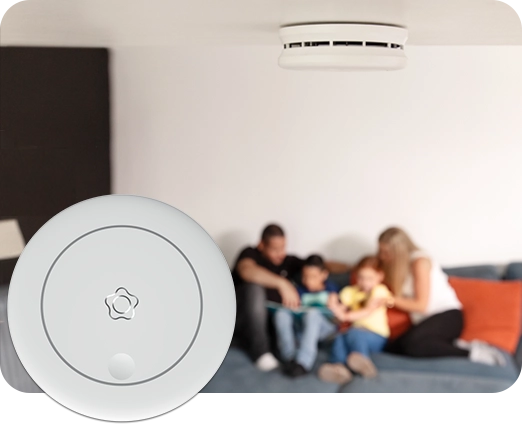 Taka-alalla perhe ja etualalla Verisuren palovaroitin.