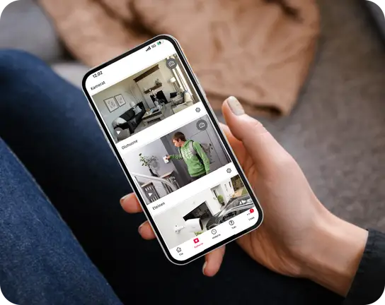 Henkilö pitää kädessään puhelinta, jossa näkyy Verisure-sovelluksen kamerat-välilehti.
