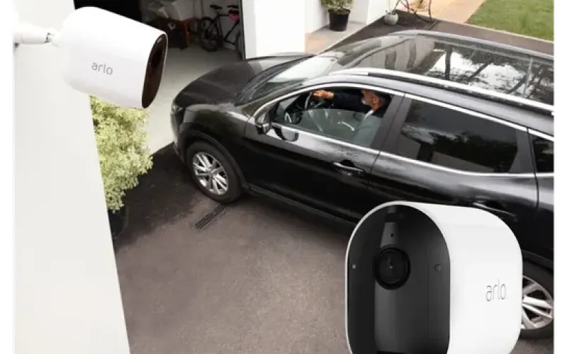 Auto ajaa autotalliin ja kuvan etualalla Arlo-valvontakamera.